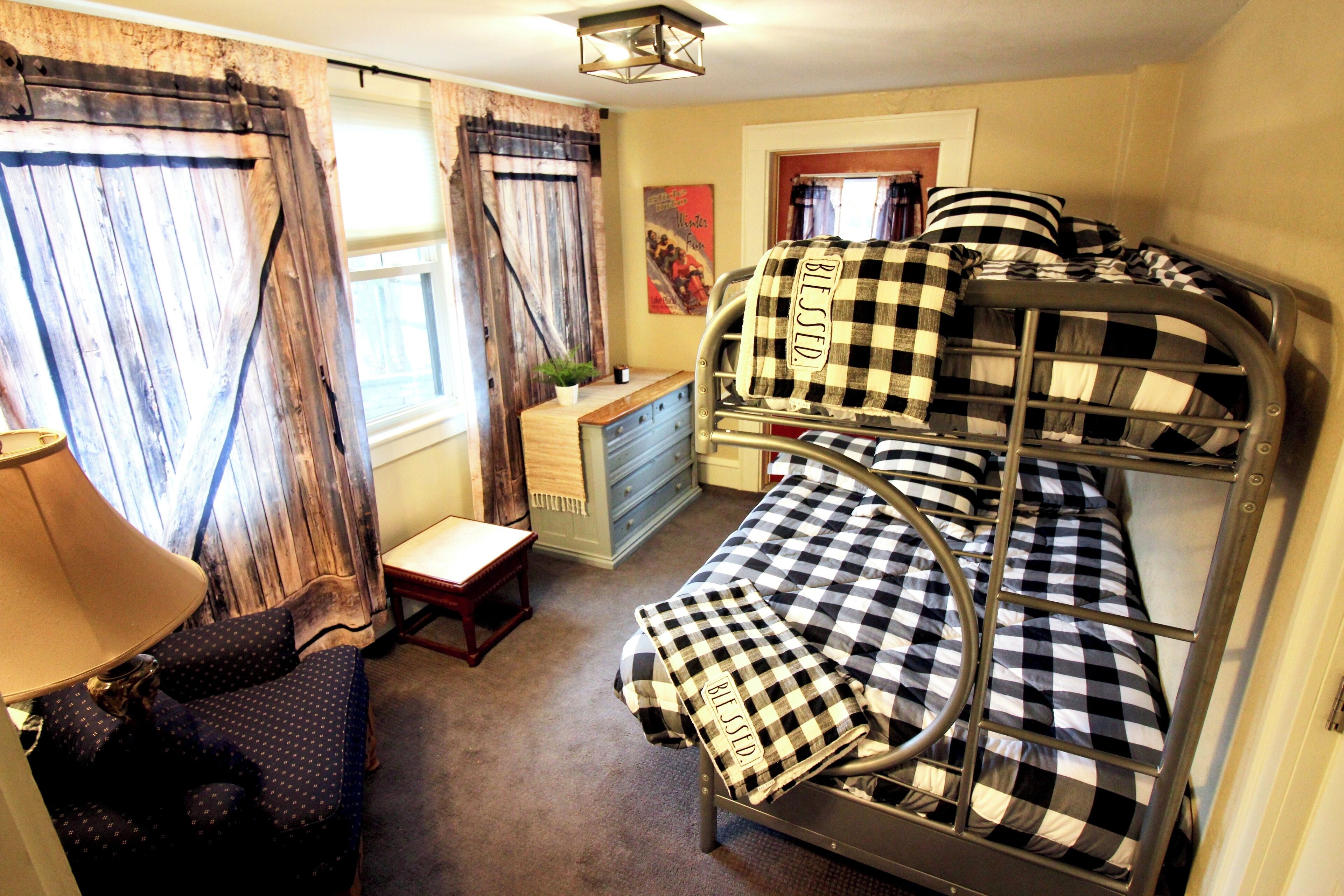 A bunk bed room with a desk, lamp, and curtains.