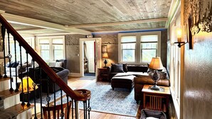 A spacious living area with a wooden staircase, a sofa set, and a coffee table.