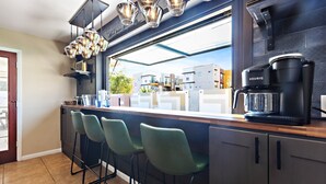 Una cocina moderna con barra, cafetera y vista al barrio.