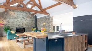 A modern kitchen with a stone wall, wooden beams, a built-in island, and a stone fireplace. - 3 bedroom accommodation in Blunts, near Saltash (Blunts, near Saltash)