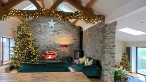 A cozy living room with a stone fireplace, a Christmas tree, and a wooden table. - 3 bedroom accommodation in Blunts, near Saltash (Blunts, near Saltash)