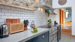 A kitchen with a stone wall, a wooden countertop, and a built-in oven. - 3 bedroom accommodation in Blunts, near Saltash (Blunts, near Saltash)