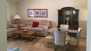 Ein Wohnzimmer mit einer Couch, einem Couchtisch und Sesseln, einem Schrank mit Glastüren und einem Deckenventilator.