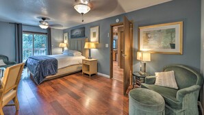 A bedroom with a bed, bedside tables, a chair, a desk, a ceiling fan, and a door leading to another room. - Near Hiking Trails: Cabin w/ Deck in Pioneer! (Pioneer)