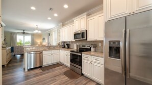 A modern kitchen with white cabinets, stainless steel appliances, and a granite countertop. - Private paradise! Gorgeous 4/3 Half duplex w/ private pool & dockage! (Marathon)