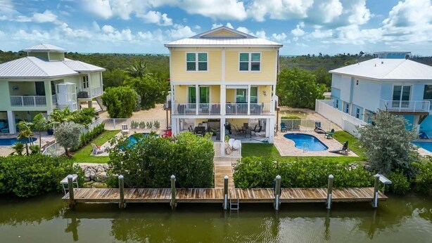 A two-story house with a pool, surrounded by greenery and a dock. - Private paradise! Gorgeous 4/3 Half duplex w/ private pool & dockage! (Marathon)