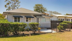 A two-story house with a covered porch, a fenced yard, and a clear sky. - Douglas 5 (Forster)