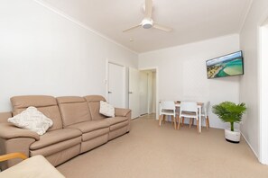 A living room with a beige sofa, a white table, and a potted plant. - Douglas 5 (Forster)