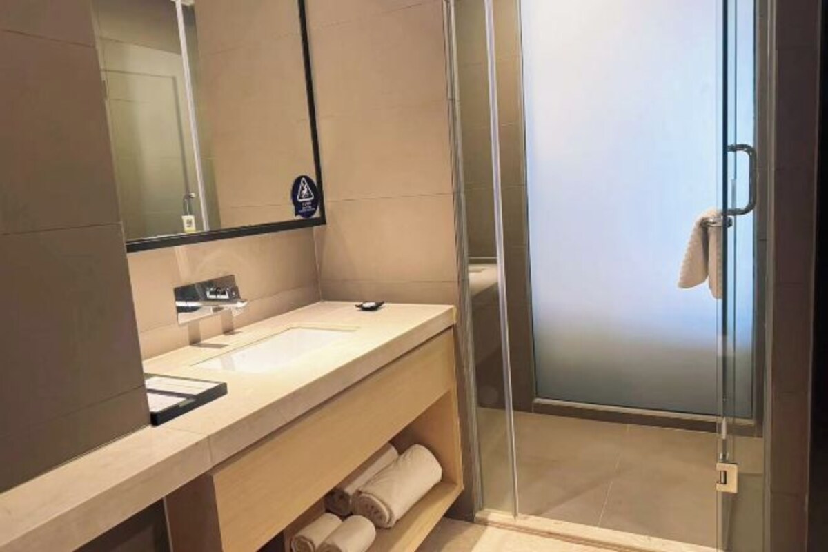 A modern bathroom with a glass shower enclosure, a sink, and a mirror.