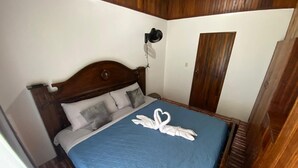 Een keurig opgemaakt bed met een blauwe quilt en handdoeken gevouwen in de vorm van twee zwanen.