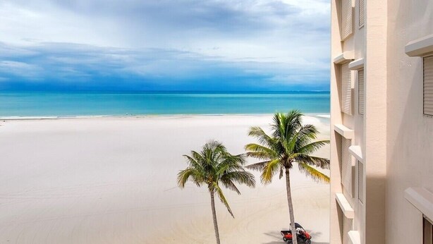 A beach view with a building on the right. - Coastal Escape ● Steps to Beach ● Sunset Views (Fort Myers Beach)