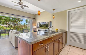 A modern kitchen with a granite countertop, stainless steel sink, and wooden cabinets. - Maui Resort Rentals: Honua Kai Hokulani 144 – Large Ground Floor 1BR, Spacious Lawn Area + Easy Pools/Beach Access (Lahaina)