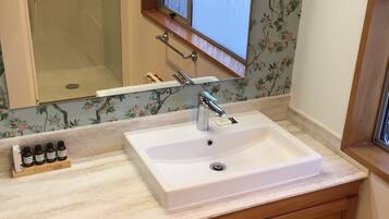 A bathroom with a white sink, wooden cabinets, a mirror, and a window with a view.