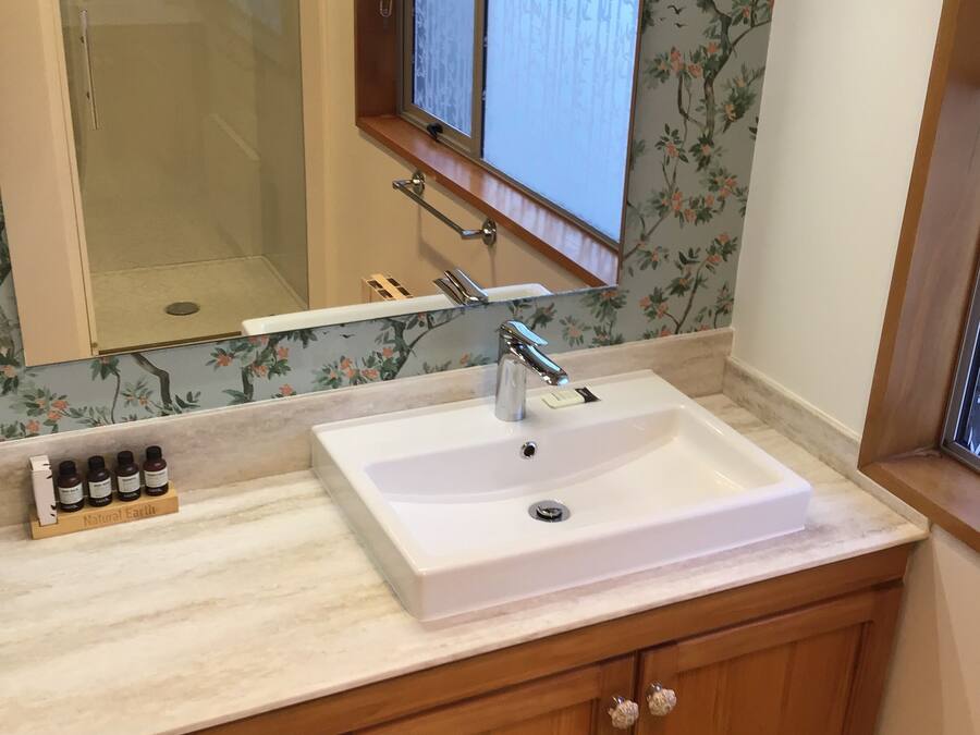 A bathroom with a white sink, wooden cabinets, a mirror, and a window with a view.