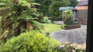 Stroll through the serene garden, surrounded by lush greenery and a brick pathway leading to a charming garden feature.