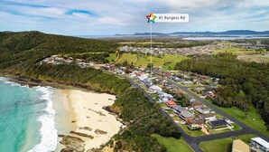 Vista aérea de una zona residencial costera con casas, una playa y una bandera que indica 41 Burgess Rd.