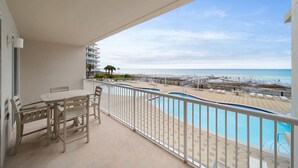 Un balcon avec piscine, vue sur la plage et espace salon extérieur.
