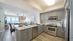 Une cuisine moderne avec des meubles gris, des appareils en acier inoxydable et un grand îlot central.
