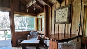 Un interior rústico de madera con barra, asientos y un gran ventanal con vistas al exterior.