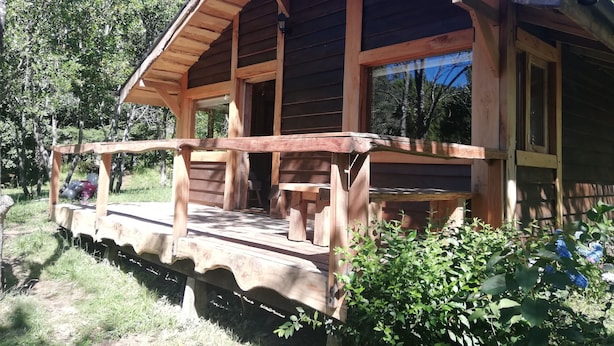 Una cabaña de madera con un porche, una ventana y una puerta.