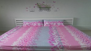 A bed with a floral bedspread and a wall decoration of a cart with flowers. - Room-t8 Guest House Don Mueang Challenge (Pak Kret)