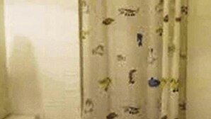 Un baño pequeño con inodoro, cortina de ducha estampada y lavamanos.