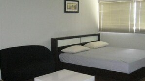 A bedroom with a bed, a chair, and a small white table.