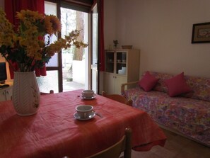 Una habitación con una mesa de comedor, un sofá, un aparador y un florero con flores.