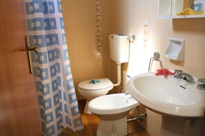 Une salle de bain équipée de toilettes, d’un bidet et d’un lavabo.
