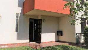 Un bâtiment doté d’une corniche rouge, d’une porte et d’un petit espace extérieur avec un chemin en briques.