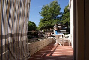 A balcony with a striped floor, a white table, and two white chairs.