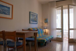 Una habitación con cama, una mesa con sillas, una lámpara y un cuadro en la pared.
