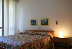 Un dormitorio con una cama, una mesita de noche, una lámpara y dos cuadros en la pared.