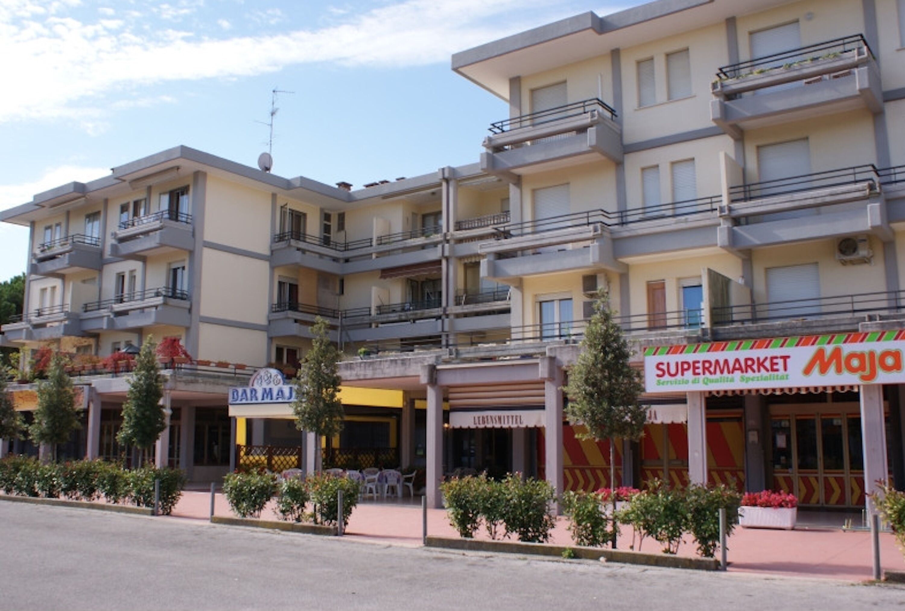 Ein mehrstöckiges Gebäude mit Geschäften im Erdgeschoss, darunter ein Supermarkt und ein Restaurant.