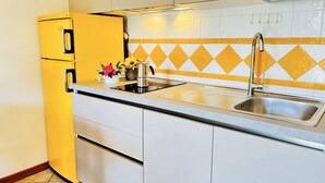 A kitchen with a yellow refrigerator, a sink, and a backsplash with yellow and white tiles. - Flat With Spacious Balcony in Bibione (San Michele al Tagliamento)