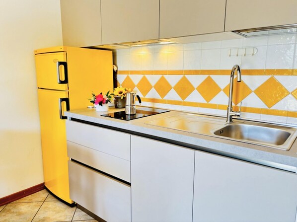 A kitchen with a yellow refrigerator, a sink, and a backsplash with yellow and white tiles.