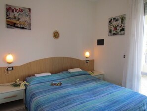 Une chambre d’hôtel comprenant un lit, deux tables de chevet, une horloge murale et deux lampes fixées au mur.