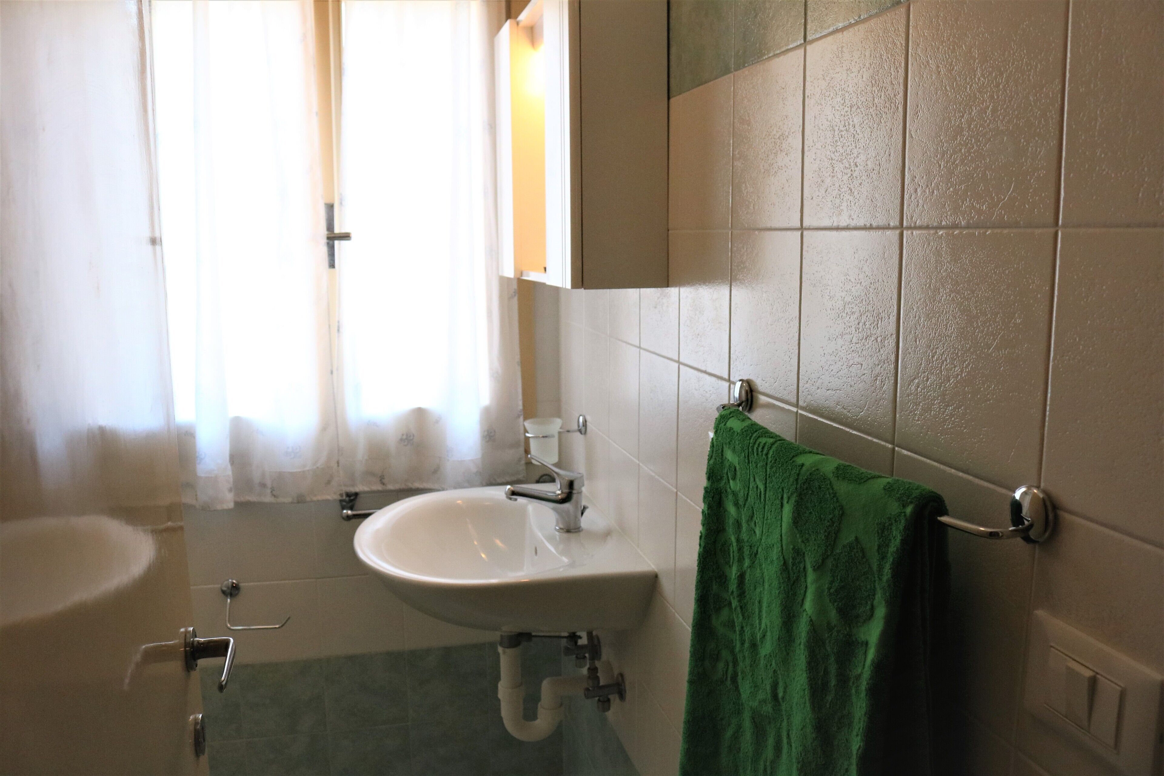 A bathroom with a sink, mirror, and towel rack.