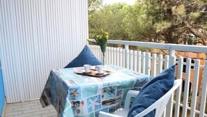 Une petite table d’extérieur recouverte d’une nappe bleue, avec des chaises blanches et une clôture blanche.