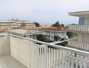 Un edificio residencial con varios balcones, suelo de baldosas y vista al mar.