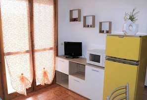 A small kitchenette with a microwave, a television, and a yellow refrigerator.