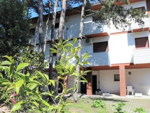 Un immeuble à plusieurs étages doté de balcons, d’une cour pavée et d’espaces verts.