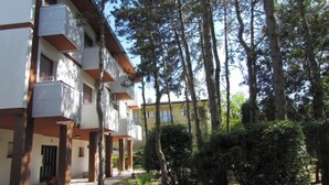 A multi-story building with balconies, surrounded by trees and greenery.