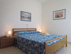 Une chambre à coucher avec un lit en bois, une table de chevet, une lampe et deux tableaux encadrés accrochés au mur.