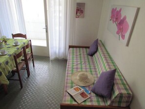 Una habitación con un sofá a cuadros, una mesa de comedor con sillas y una puerta que da al exterior.