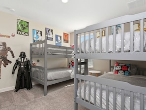 Ein Kinderzimmer mit Etagenbetten, Star Wars Postern und einer Darth-Vader-Figur.