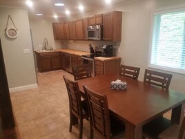 Una cocina con armarios de madera, microondas y una mesa de comedor con sillas.