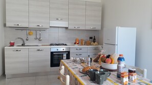 A modern kitchen with white cabinetry, a gas stove, a built-in oven, and a refrigerator. - Charming Holiday Home Near The Beach With A Terrace Parking Available, Pets (Melendugno)
