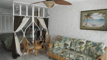 Relax in this serene room with a comfortable sofa, dining table, and ceiling fan.