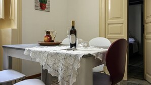 A dining table with a lace tablecloth, a bottle of wine, and a pitcher on it. - Palazzo Nicastro Guest House Red (Avola)